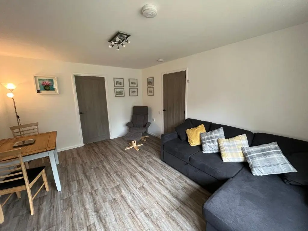 a living room with a couch and a table and a desk at The Wee Hoose near Loch Ness, private garden, private parking in Drumnadrochit