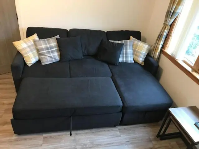 a blue couch with pillows in a living room at The Wee Hoose near Loch Ness, private garden, private parking in Drumnadrochit