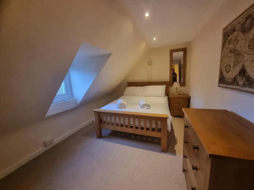 a attic bedroom with a bed and a window at Rose Cottage City Centre in Inverness