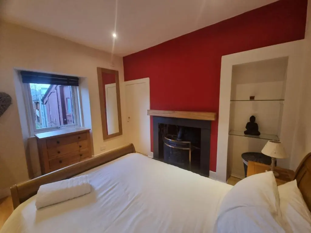 a bedroom with a white bed and a fireplace at Rose Cottage City Centre in Inverness