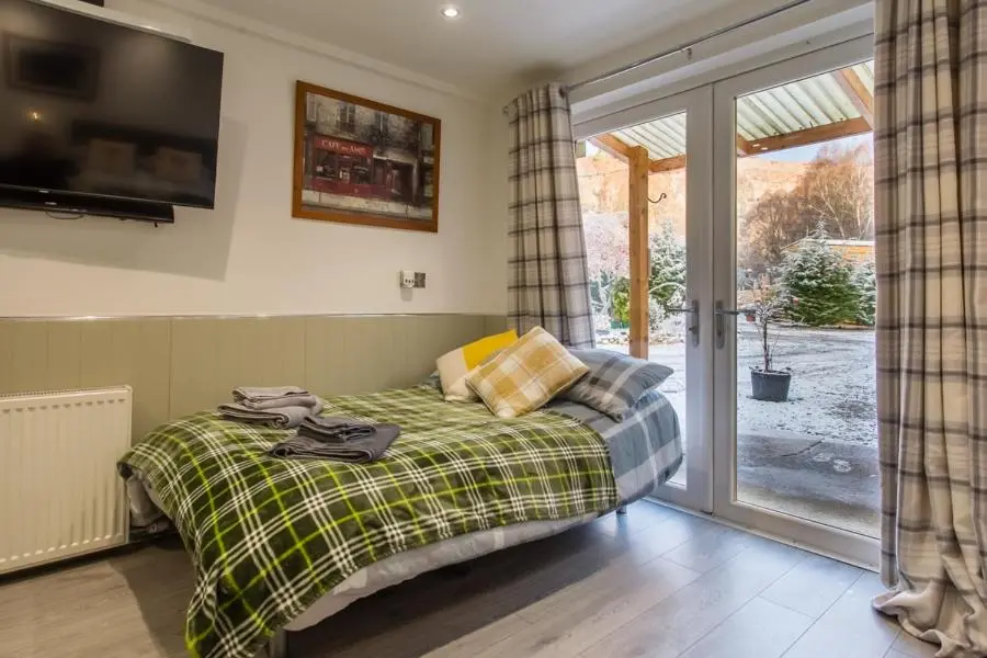 a bedroom with a bed and a sliding glass door at Highland Retreats Cannich in Cannich