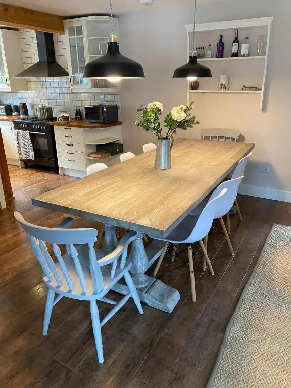 a kitchen with a wooden table and chairs at Highland Hideaway in secluded riverside location in Garve