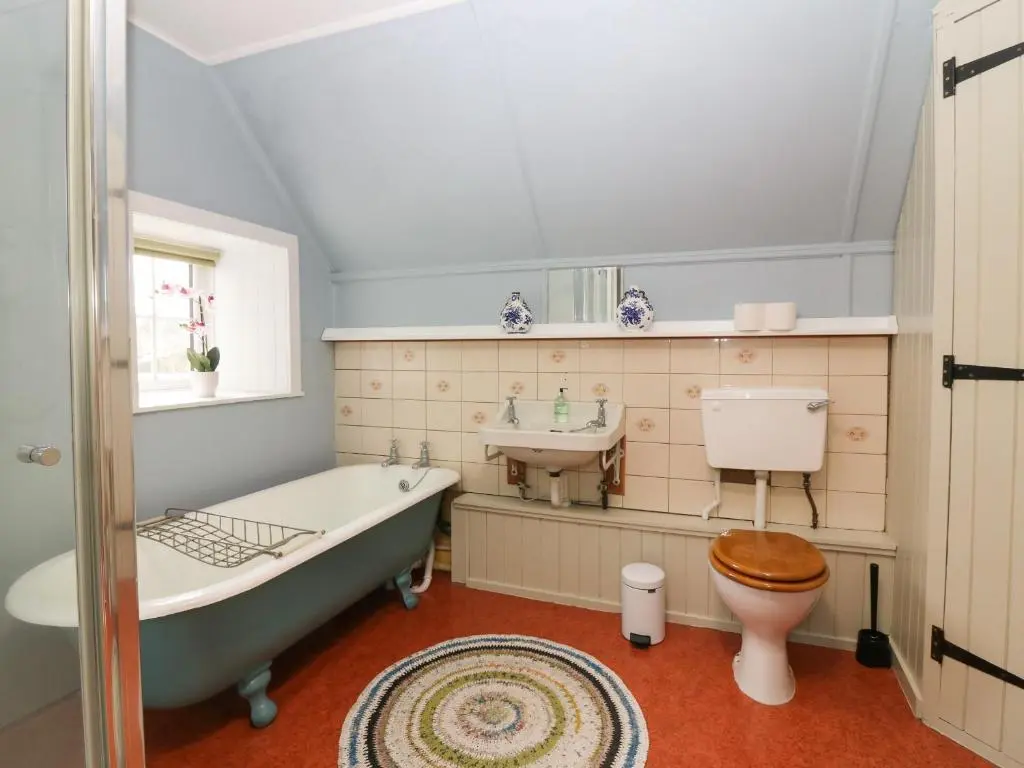 a bathroom with a tub and a toilet and a sink at Garden Cottage in Elgin