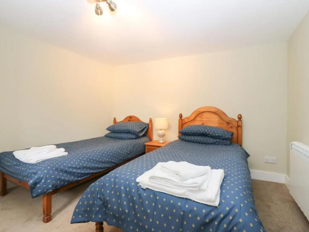 two twin beds in a bedroom with blue comforter at Garden Cottage in Elgin