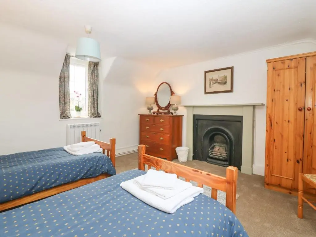 a bedroom with two beds and a fireplace at Garden Cottage in Elgin
