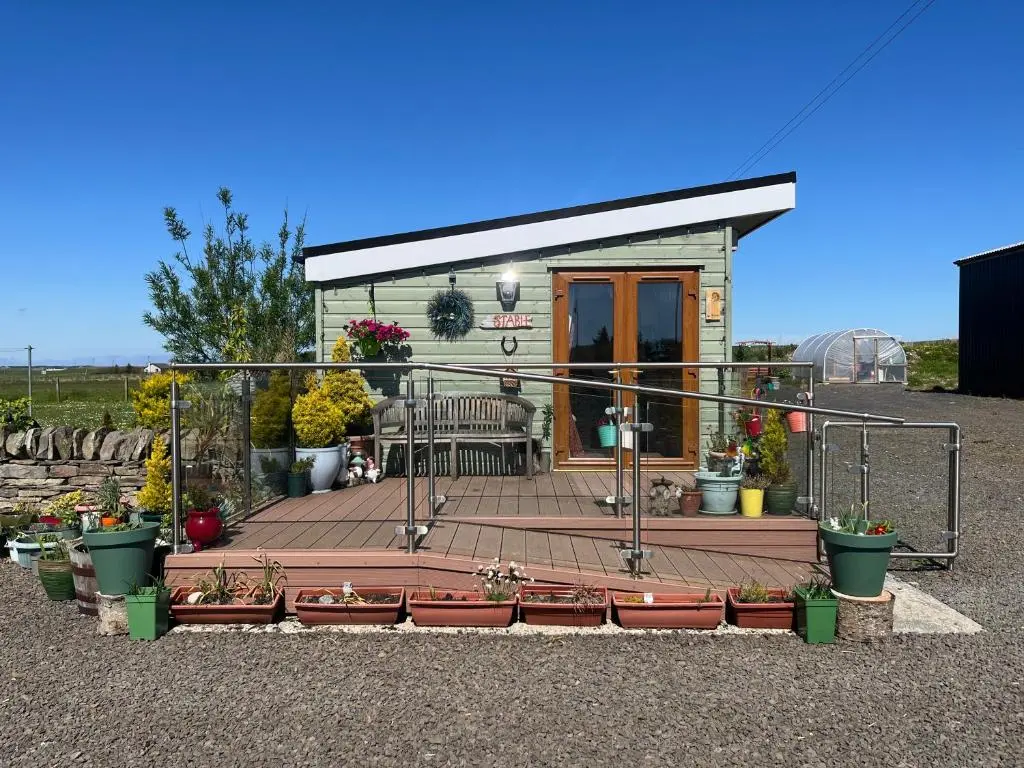 a small house with a deck with plants and flowers at The Stable - NC500 in Wick