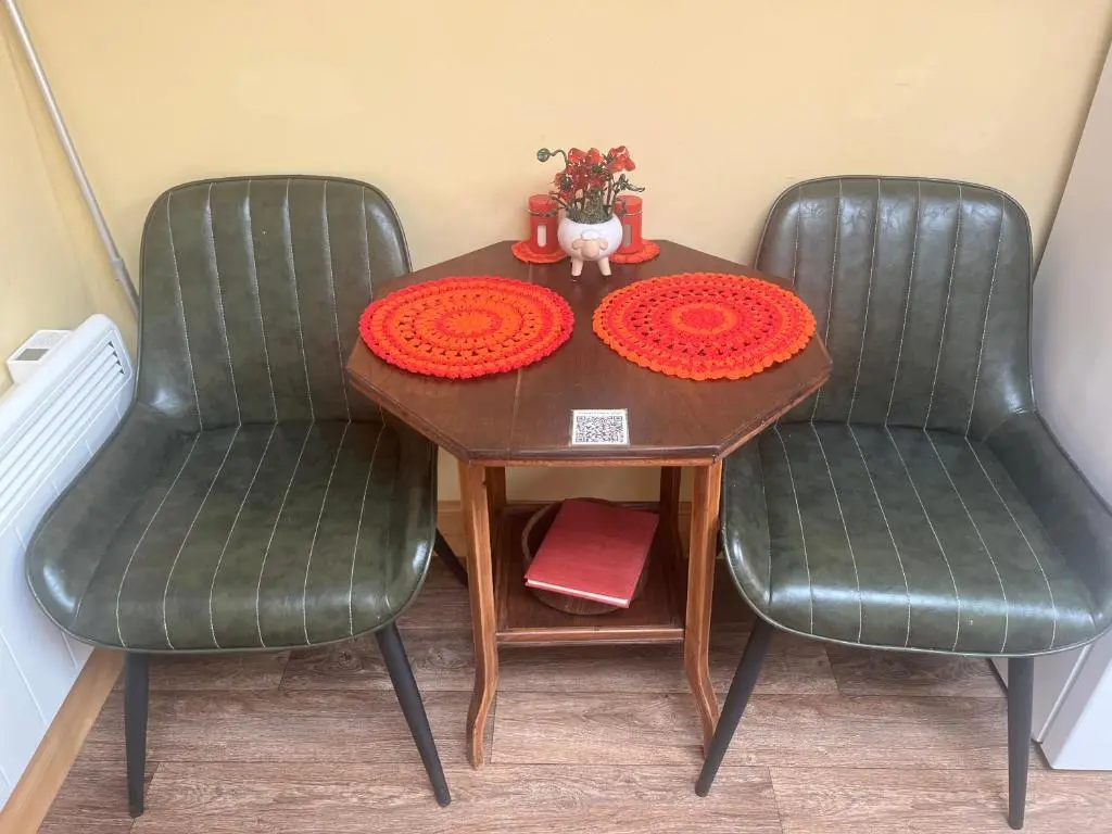 a table with two green chairs and a table with flowers at The Stable - NC500 in Wick