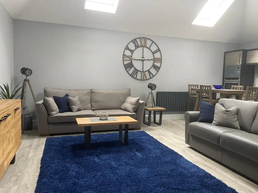 a living room with a couch and a table and a clock at The Store by Caithness Luxury Apartments NC500 - Luxury modern conversion with open plan living - Sleeps 4 in Wick