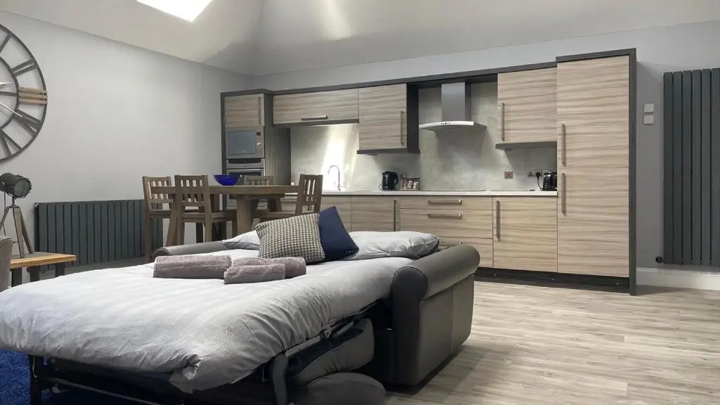 a bedroom with a large bed and a kitchen at The Store by Caithness Luxury Apartments NC500 - Luxury modern conversion with open plan living - Sleeps 4 in Wick