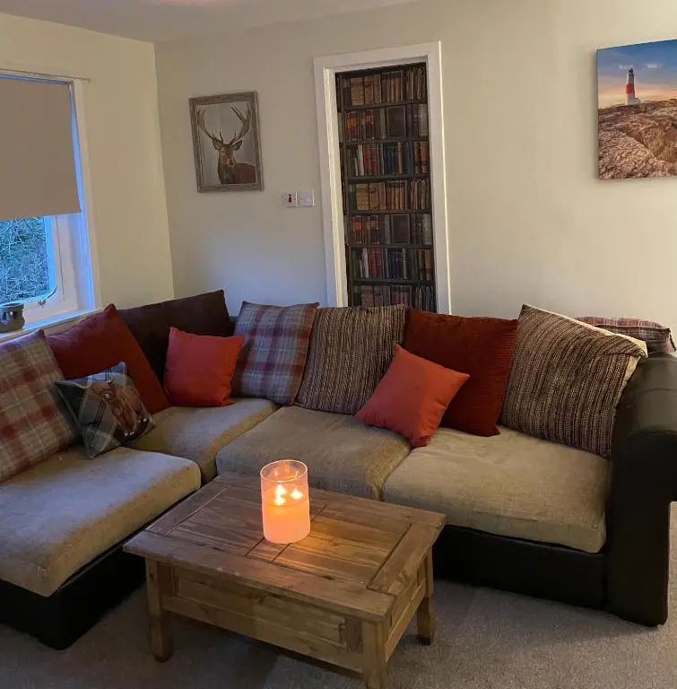 a living room with a couch and a candle on a table at Charleston Apartment Self Catering 5 min drive from town centre in Inverness
