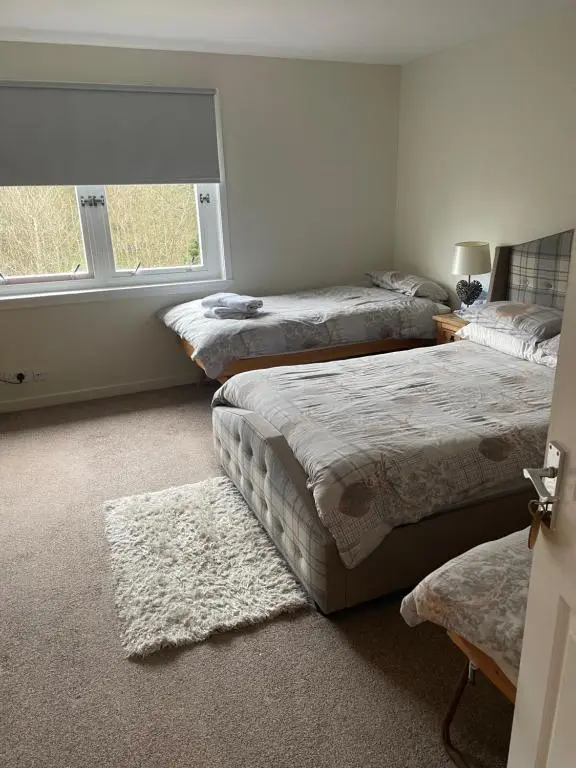 a bedroom with three beds and a window at Charleston Apartment Self Catering 5 min drive from town centre in Inverness