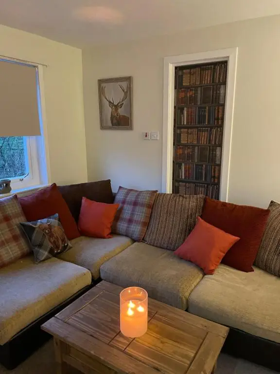 a living room with a couch and a candle on a table at Charleston Apartment Self Catering 5 min drive from town centre in Inverness