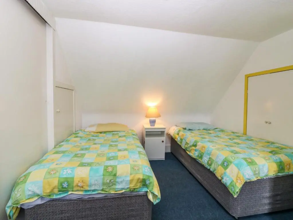 a bedroom with two beds and a lamp on a table at Dookers' Hoose in Buckie