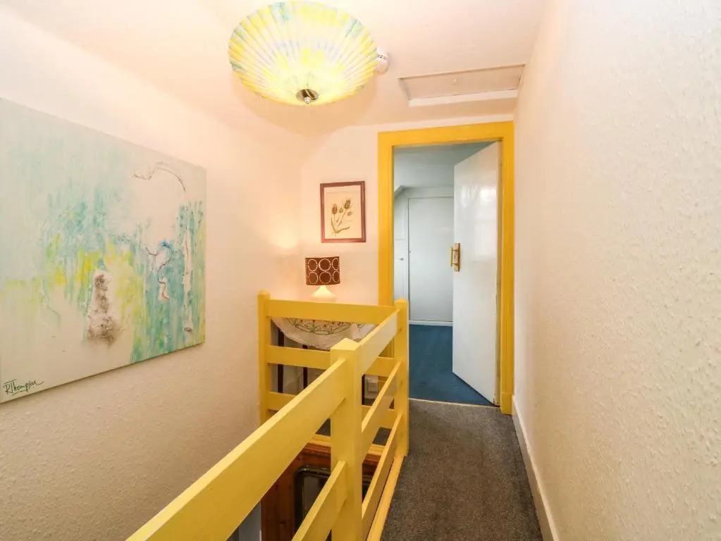 a hallway with a staircase and a painting on the wall at Dookers' Hoose in Buckie