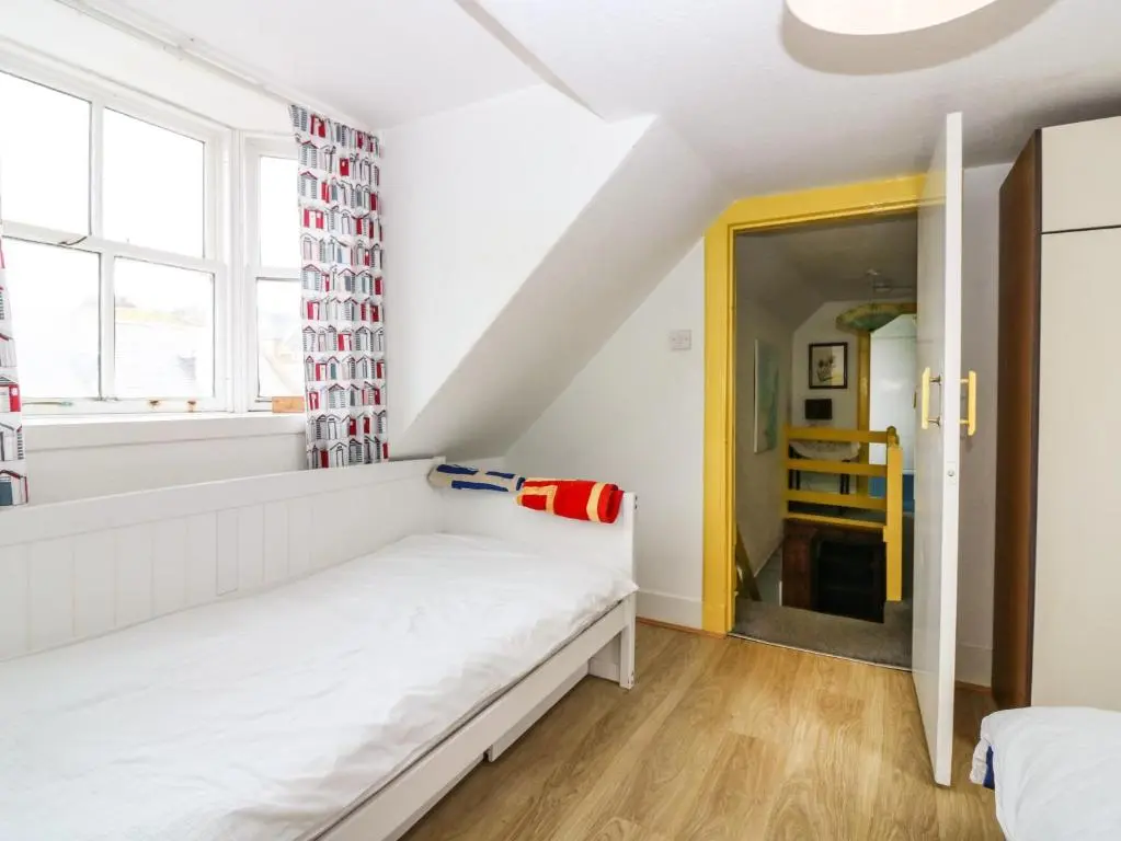 a bedroom with a white bed and a window at Dookers' Hoose in Buckie