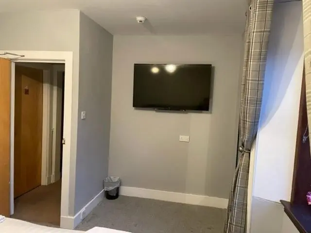 a bedroom with a flat screen tv on the wall at Commercial Hotel (Insch) in Insch