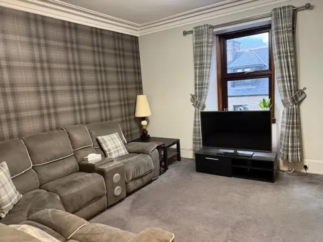 a living room with a couch and a flat screen tv at Commercial Hotel (Insch) in Insch