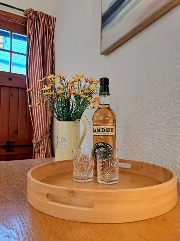 a bottle of alcohol sitting on a table with a glass at Old Tavern House in Fortrose