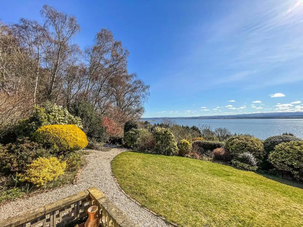 a garden with a path next to the water at Chanonry View Holiday Cottage in Fortrose