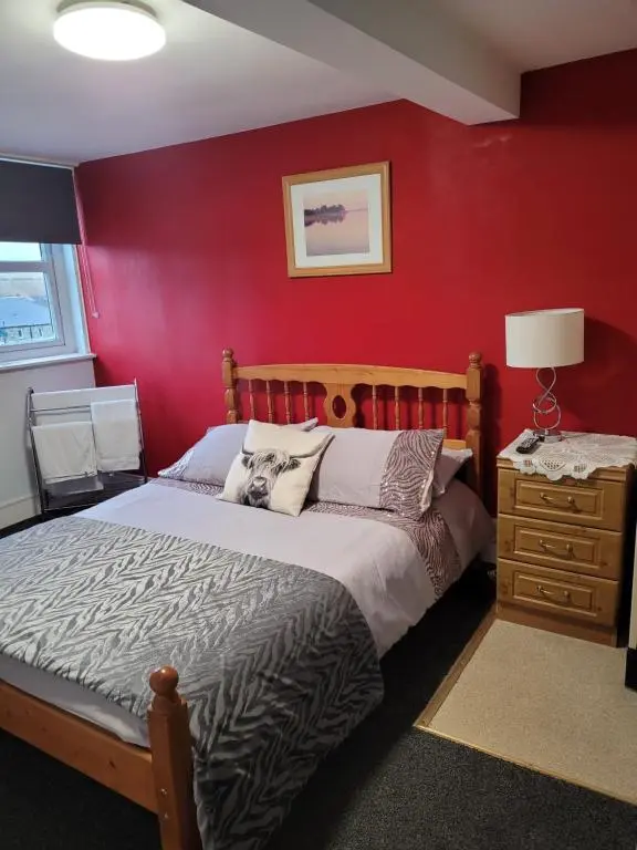 a bedroom with a bed and a red wall at White Horse Hotel in Strichen