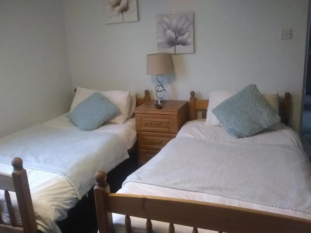 a bedroom with two beds and a wooden dresser at White Horse Hotel in Strichen