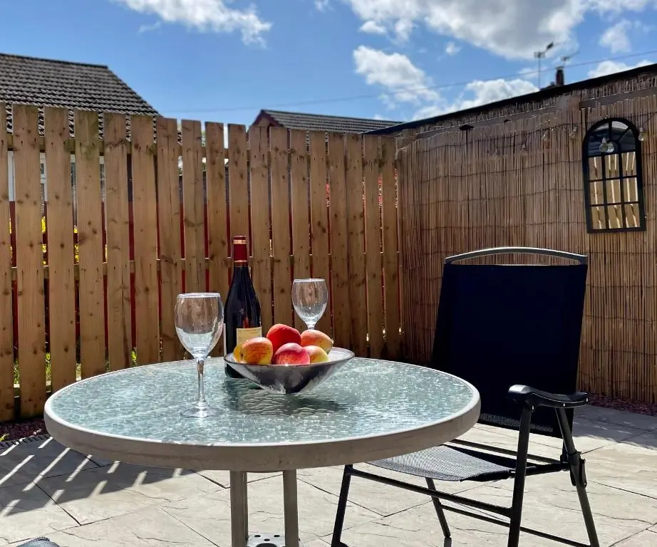a table with a bowl of fruit and two wine glasses at The Smiddy in Inverness