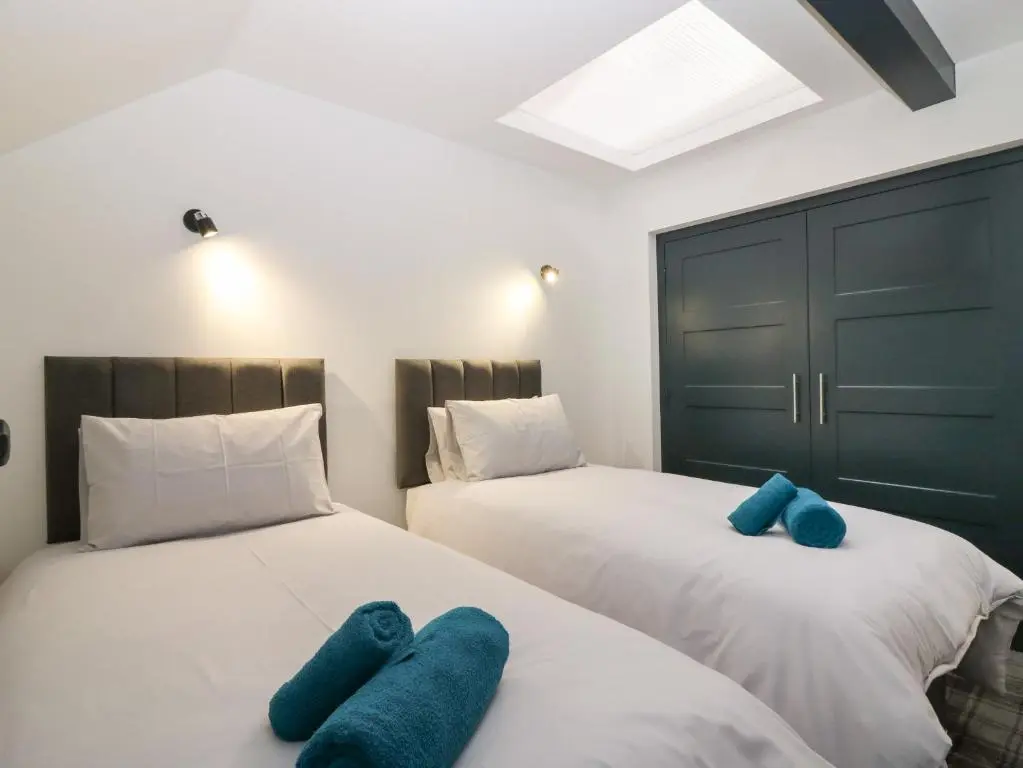 two beds in a room with blue pillows on them at The Dance Hall, The Institute Executive Apartments in Keith