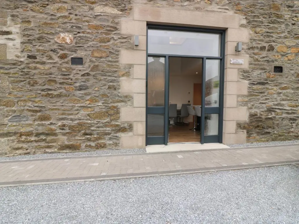 a glass door of a building with a stone wall at The Dance Hall, The Institute Executive Apartments in Keith