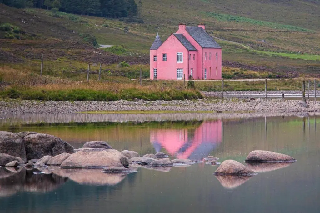 a pink house is reflected in a body of water at Cuillich Mill Bed and Breakfast in the Highlands in Alness