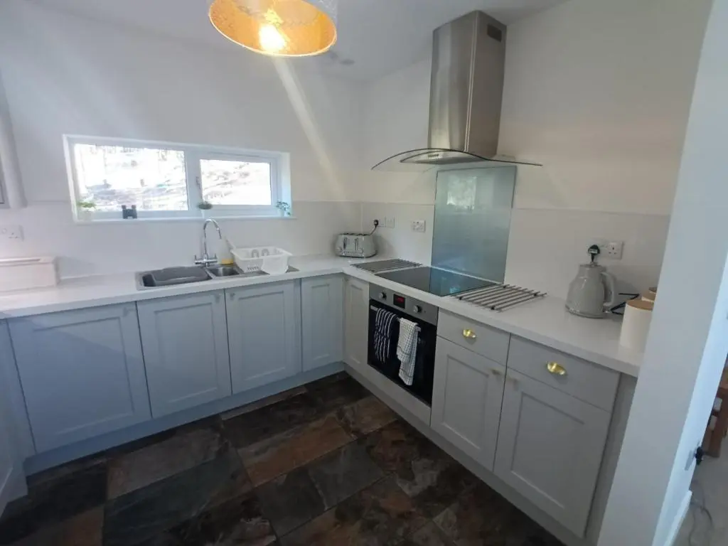 a kitchen with white cabinets and a stove top oven at Sawmill Cottage in Grantown on Spey