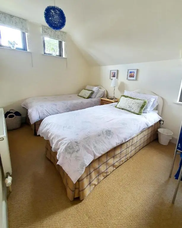 two beds in a bedroom with two windows at Lindas Retreats Self catering accommodation 1 bedroom cottage or 3 bedroom House in Tomintoul