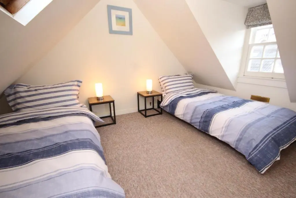 two beds in a attic room with two lamps at Zen Cottage Cullen - Sleeps 4 Garden & Pets Ok in Cullen