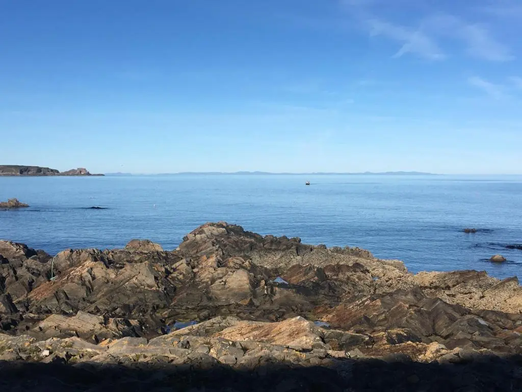 a large body of water with rocks and the ocean at Zen Cottage Cullen - Sleeps 4 Garden & Pets Ok in Cullen