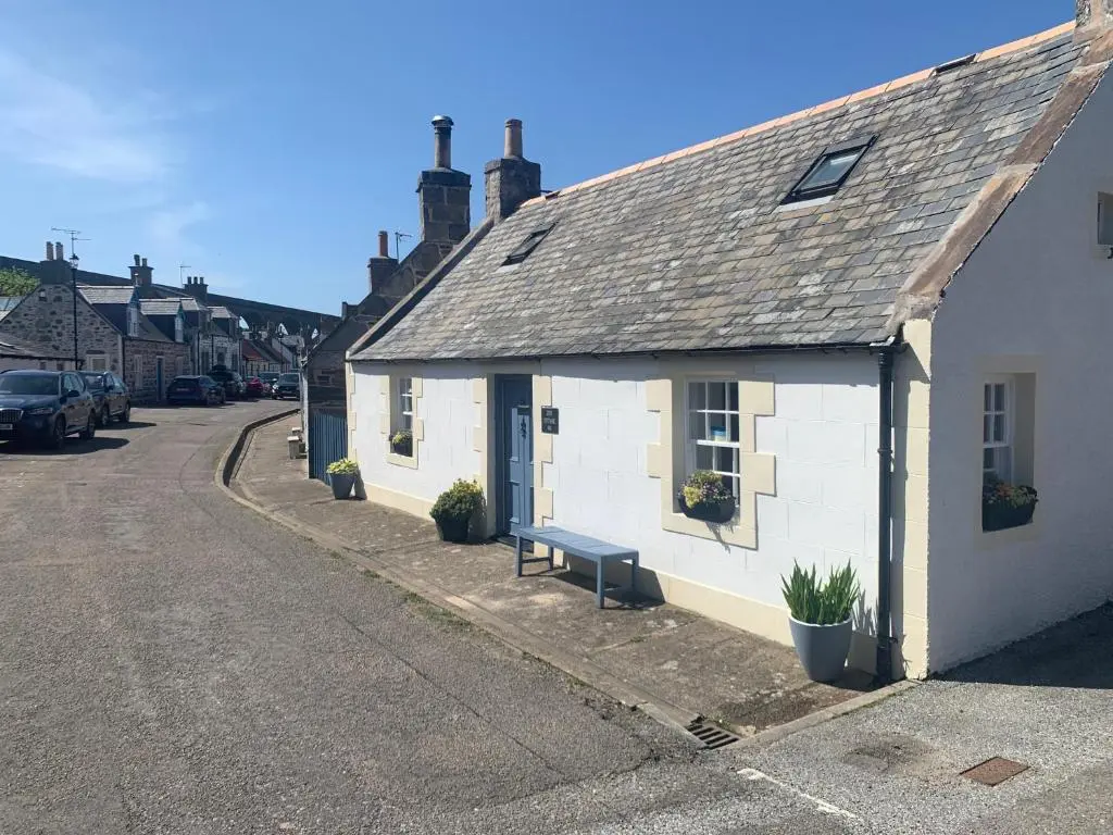 a white building with a bench next to a street at Zen Cottage Cullen - Sleeps 4 Garden & Pets Ok in Cullen