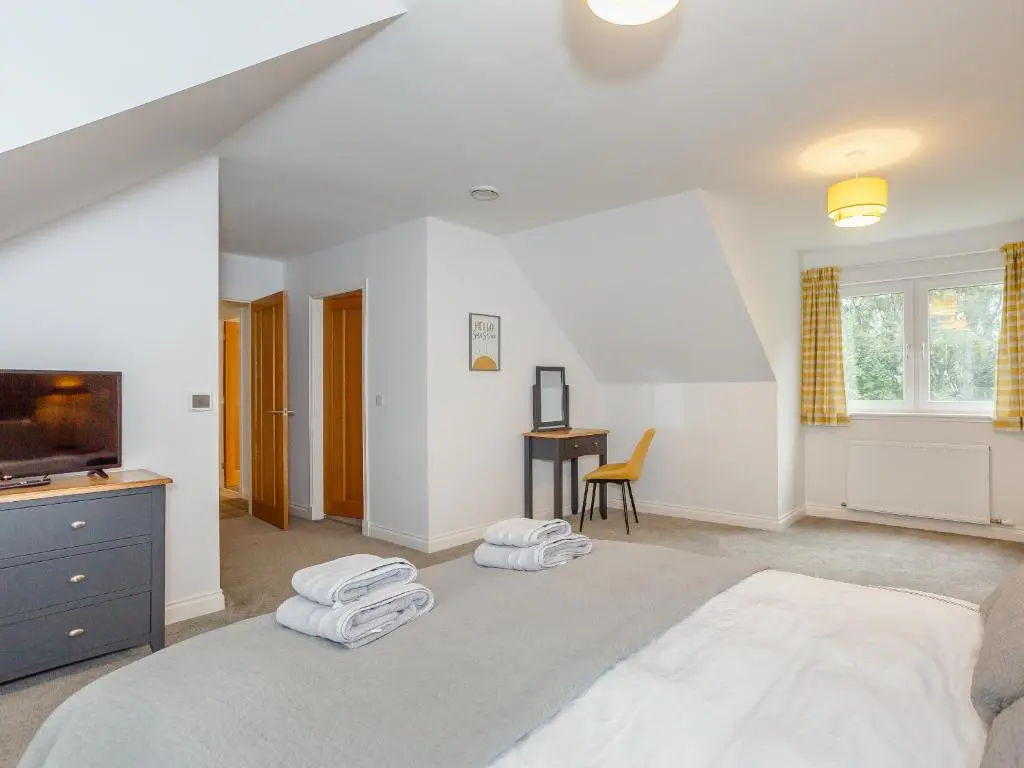 a bedroom with a large bed and a desk at Strathclaggan in Aberlour