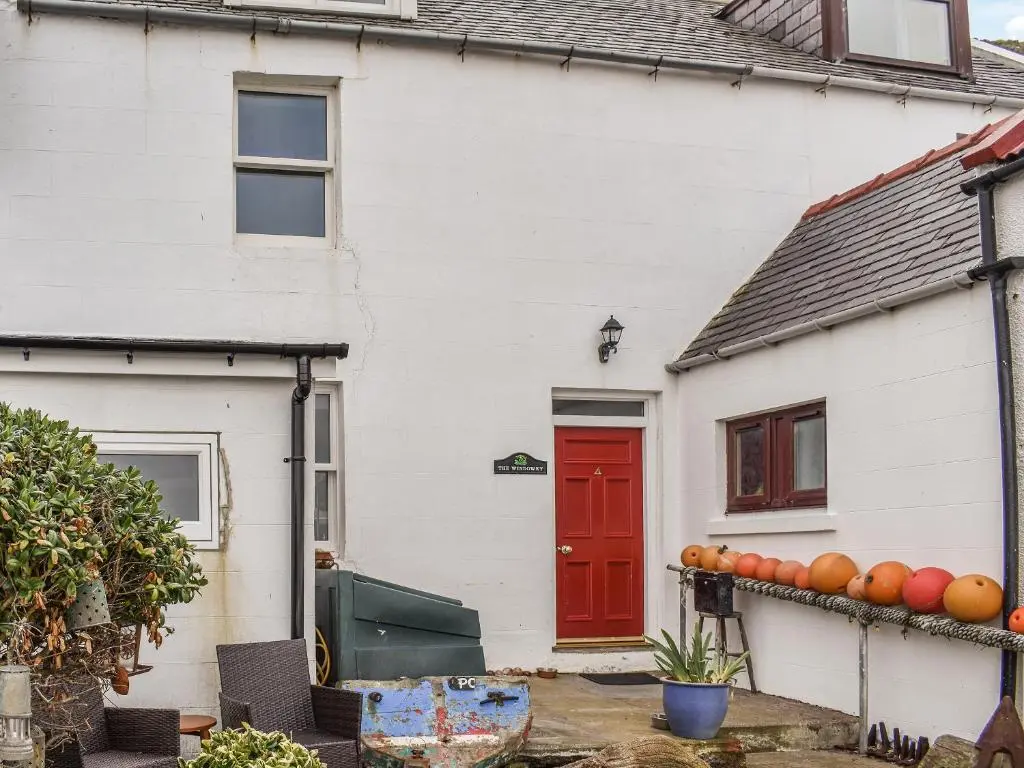 a white house with a red door and oranges at The Windowky in Gardenstown