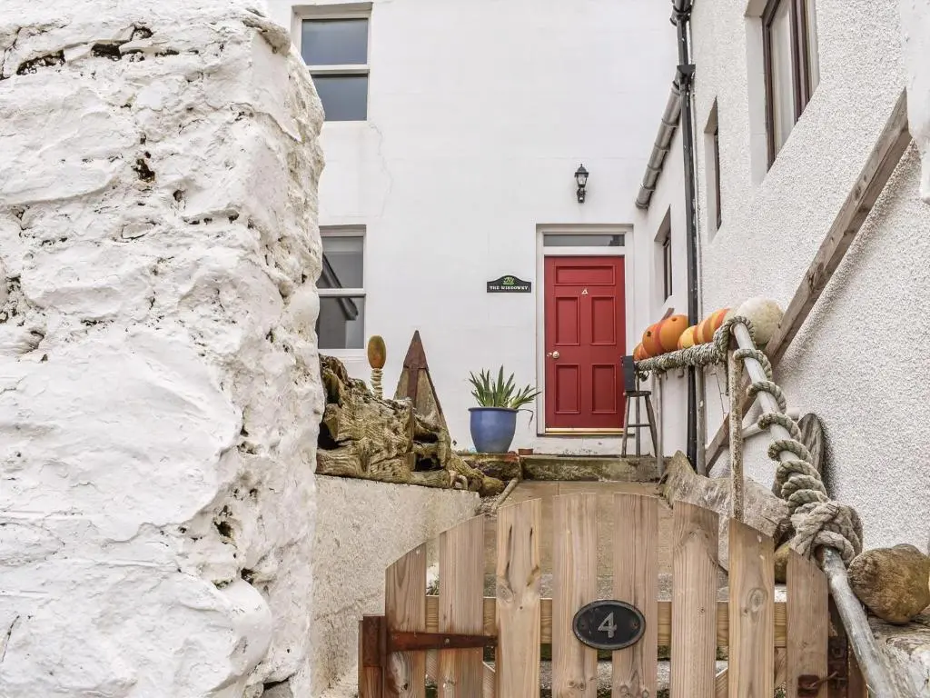 a house with a red door and a wooden gate at The Windowky in Gardenstown