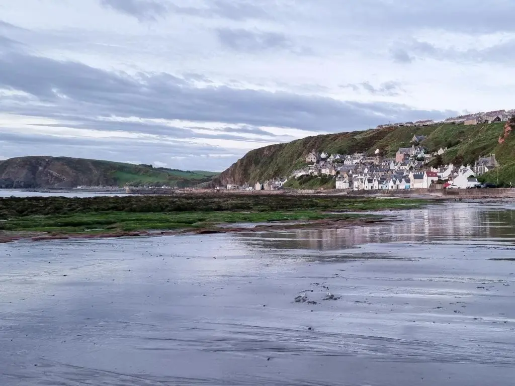 a view of a beach with a town in the background at The Windowky in Gardenstown