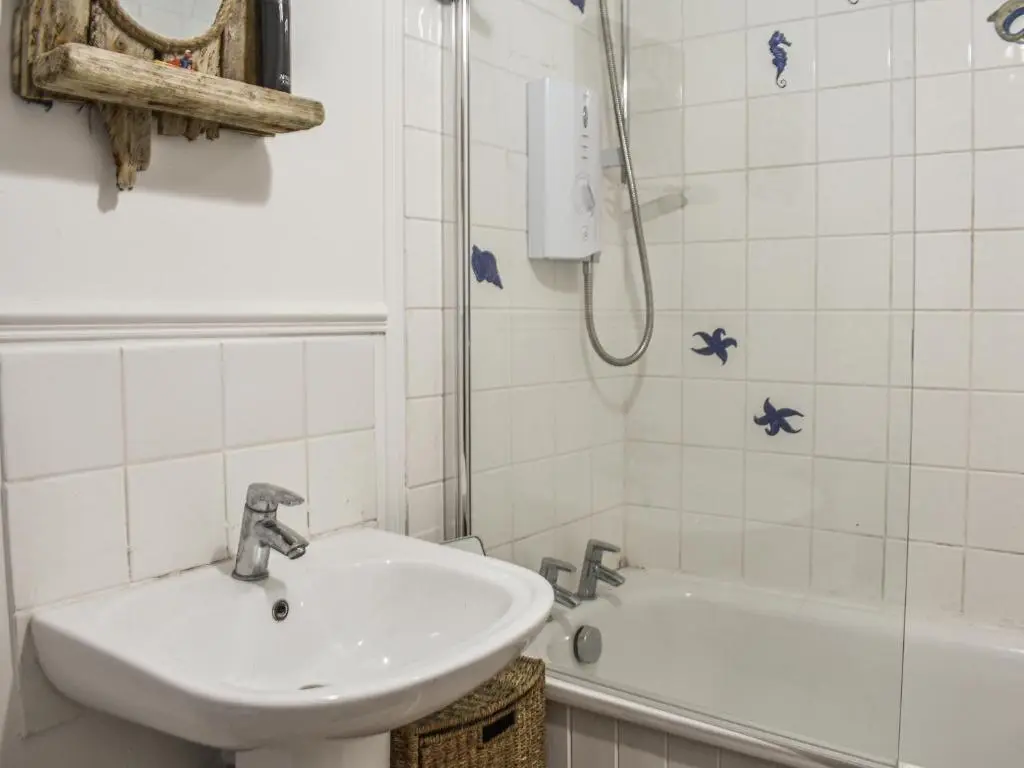 a white bathroom with a sink and a shower at The Windowky in Gardenstown