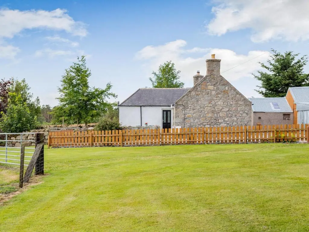 an old stone house with a wooden fence at Glen Nevis Cottage in Port Elphinstone