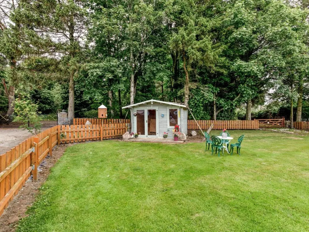 a backyard with a small shed with a table and chairs at Glen Nevis Cottage in Port Elphinstone