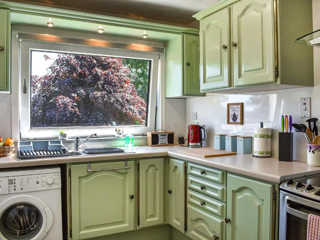 a kitchen with green cabinets and a window at Glen Nevis Cottage in Port Elphinstone