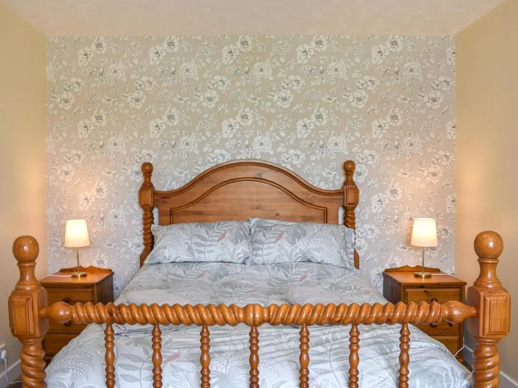 a bedroom with a wooden bed with two night stands at Glen Nevis Cottage in Port Elphinstone