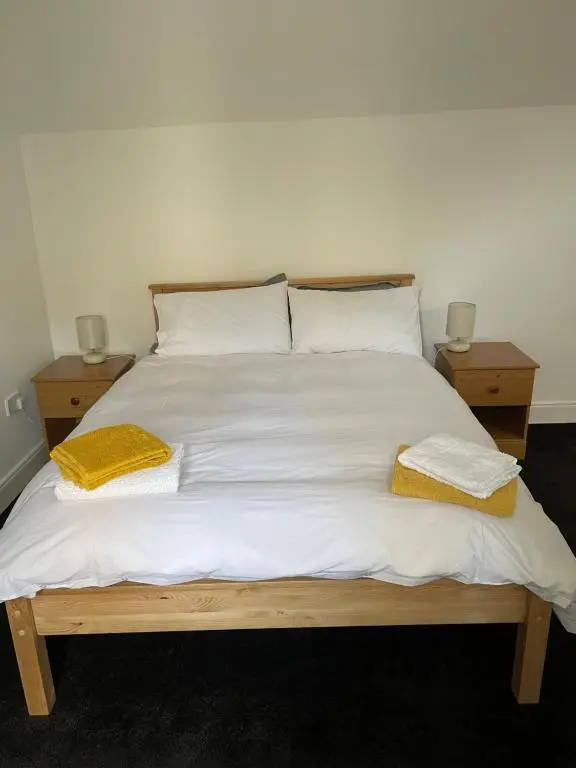 a bed with two pillows and two night stands at Newsagents Flat in Lairg