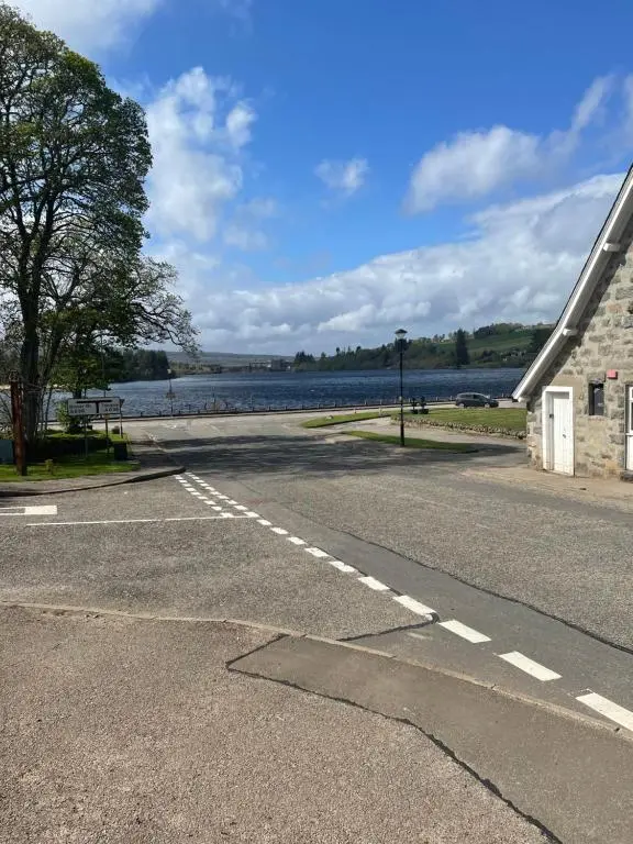 an empty road next to a body of water at Newsagents Flat in Lairg