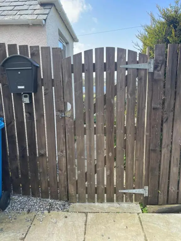 a wooden fence in front of a house at Newsagents Flat in Lairg