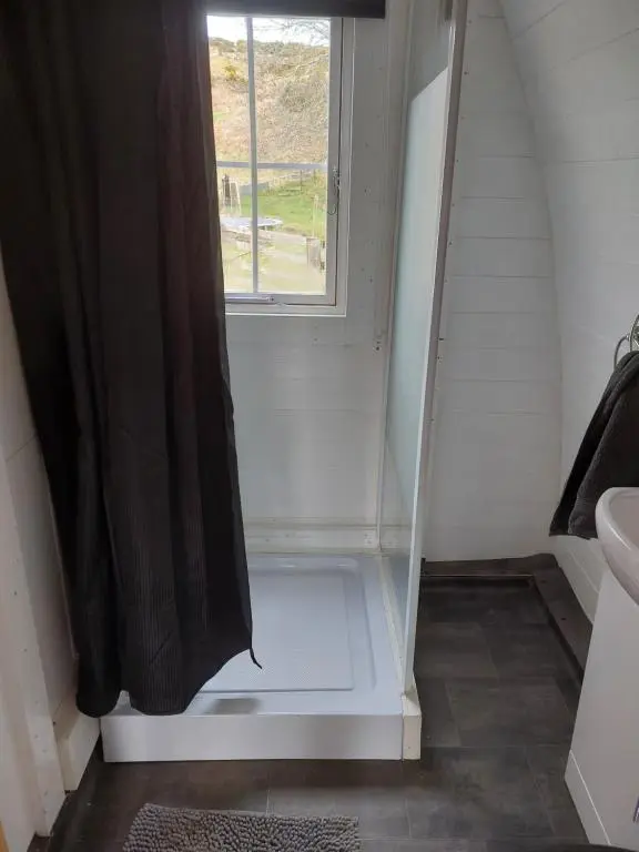 a bathroom with a shower curtain and a sink at Pod 4 in Skail