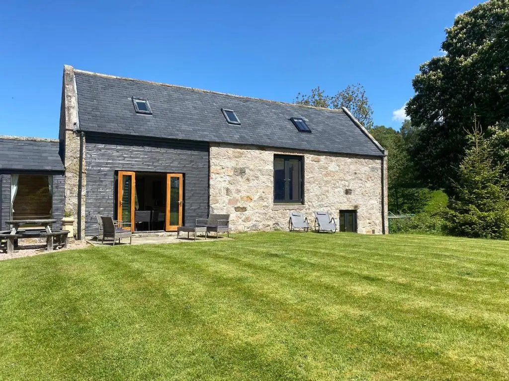 a stone cottage with a lawn in front of it at Crofts Mill in Ballater