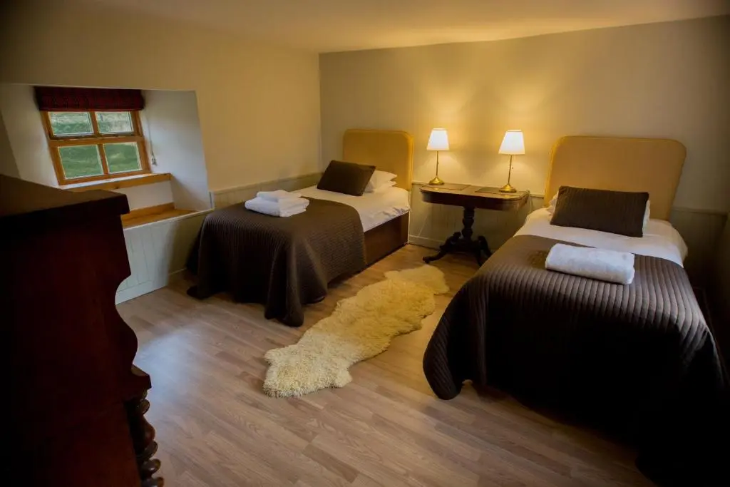 a room with two beds and a rug at Crofts Mill in Ballater