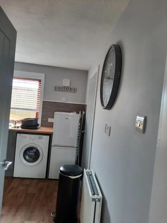 a kitchen with a refrigerator and a clock on a wall at Ella's Hoose in Wick
